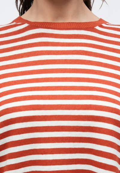 Πλεκτό τοπ με κόκκινες και λευκές ρίγες και στρογγυλή λαιμόκοψη. Διαθέτει ομοιόμορφα κατανεμημένες οριζόντιες ρίγες, λεία υφή και απαλό ύφασμα.