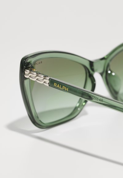 Occhiali da sole cat-eye verdi con lenti sfumate. La montatura presenta una finitura lucida e dettagli in argento testurizzati sulle aste con il logo "RALPH".