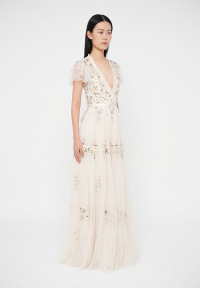 Oblečenie vyšívané kvetinovým vzorom v bledo béžovej farbe, s priehľadnými rozšírenými rukávmi, hlbokým výstrihom do V a splývavou sukňou s viacvrstvovou štruktúrou z tulu.