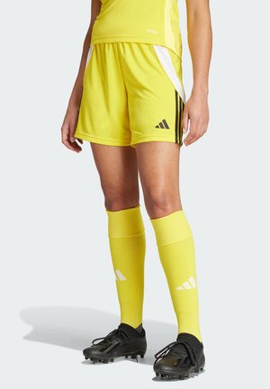 Gele sokkermouwen met zwarte strepen, gecombineerd met gele kniekousen. Zwarte voetbalschoenen hebben veters en een gestroomlijnd ontwerp.