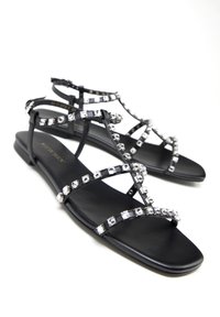 Zwarte platte sandalen met gekruiste banden, versierd met heldere kristallen langs de randen, met een glad matte afwerking en een rechthoekige teen.