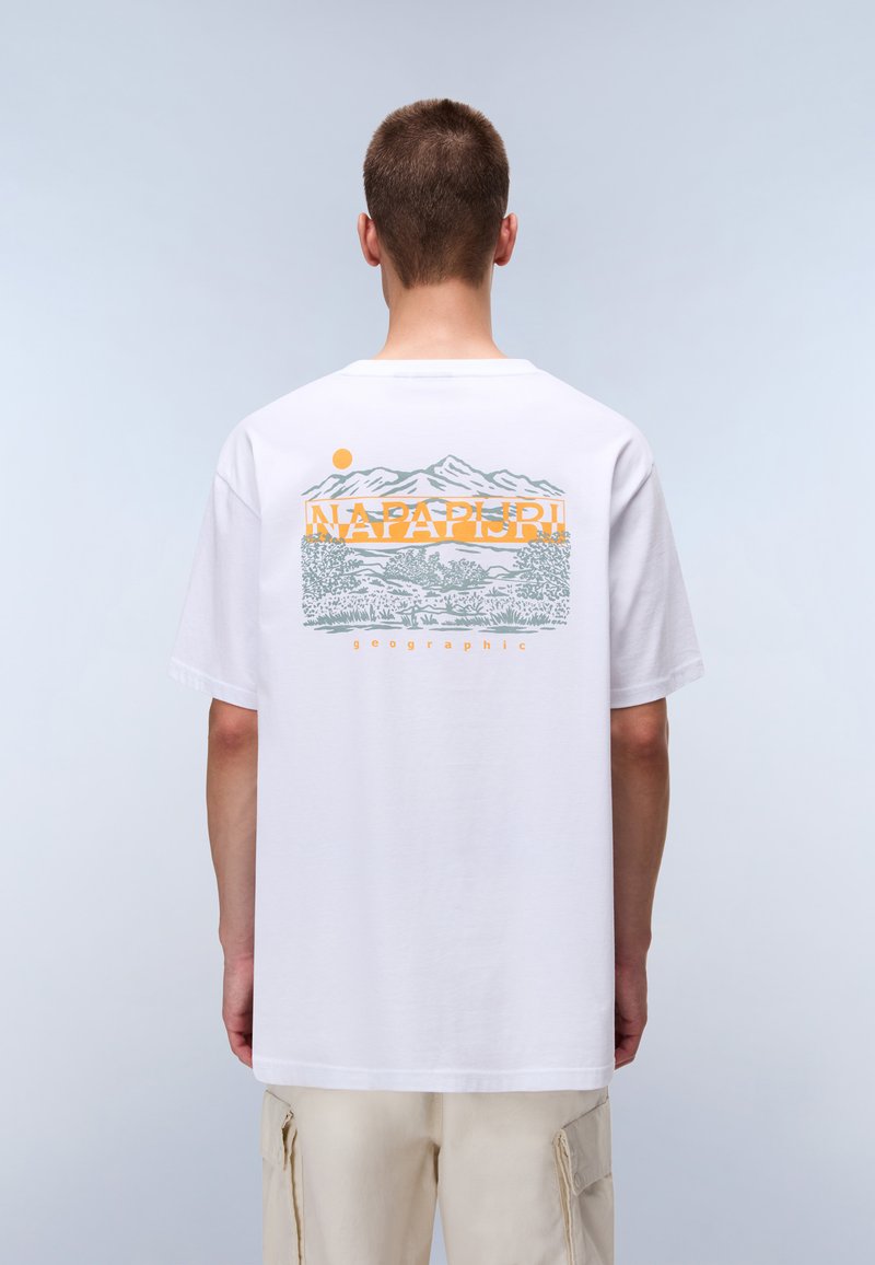 Vit bomullst-shirt med en grafisk design av berg och träd i grått och orange på ryggen, med korta ärmar och rund halsringning.