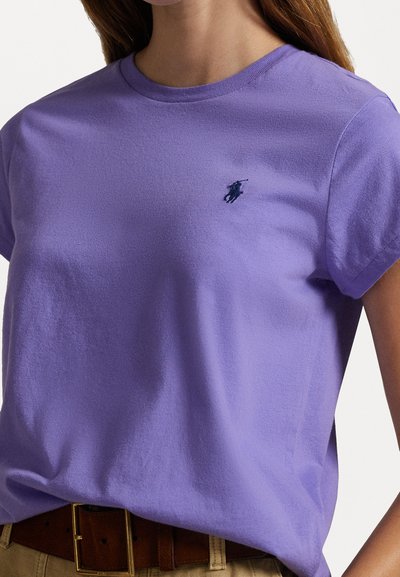 T-shirt di cotone viola con colletto a girocollo e maniche corte, caratterizzata da un piccolo logo navy sul petto. Tessuto morbido, design casual.
