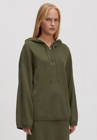 Olijfgroene hoodie met een ritssluiting aan de voorkant, relaxte pasvorm en ribgebreide manchetten en zoom. Gemaakt van textiel met structuur, geschikt voor casual draagstijl.