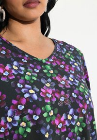 Top in tessuto a fantasia floreale con scollo a V. Sfondo scuro con fiori colorati in viola, verde e bianco, abbellito con strass.