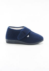 Zapatilla de color azul marino con tejido suave y texturizado, correa de velcro y un acento en forma de corazón en el lado. Forro de forro polar blanco y suela negra.