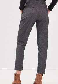 Grå, skräddarsydda byxor i texturerat tyg, med smal passform, uppvikta fållar och två bakfickor. Bärs med bruna ankelstövlar.