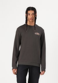 Dark gray long-sleeve sweatshirt featuring a small colorful graphic on the left chest, ribbed cuffs, and a relaxed fit.