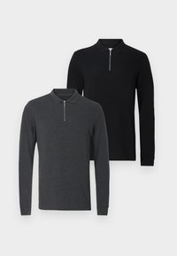 Δύο πόλο μπλούζες με μακριά μανίκια: η μία σκούρο γκρι με φερμουάρ στο γιακά και η άλλη μονόχρωμη μαύρη, και οι δύο με κλασική εφαρμογ ή και απαλό ύφασμα.