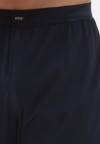 Marineblauwe shorts van een gladde stof, met een elastische tailleband waarop een logo aan de voorkant is afgebeeld. Eenvoudig ontwerp, geen patronen.