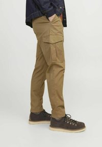 Khaki cargo pants met meerdere zijzakken, rechte pasvorm, gemaakt van een stevige katoenmix. Gecombineerd met donkere wandelschoenen.