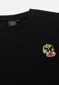 Zwarte katoenen t-shirt met een ronde halslijn en een kleurrijk geborduurd logo op de borst, met gele, zwarte en rode details.
