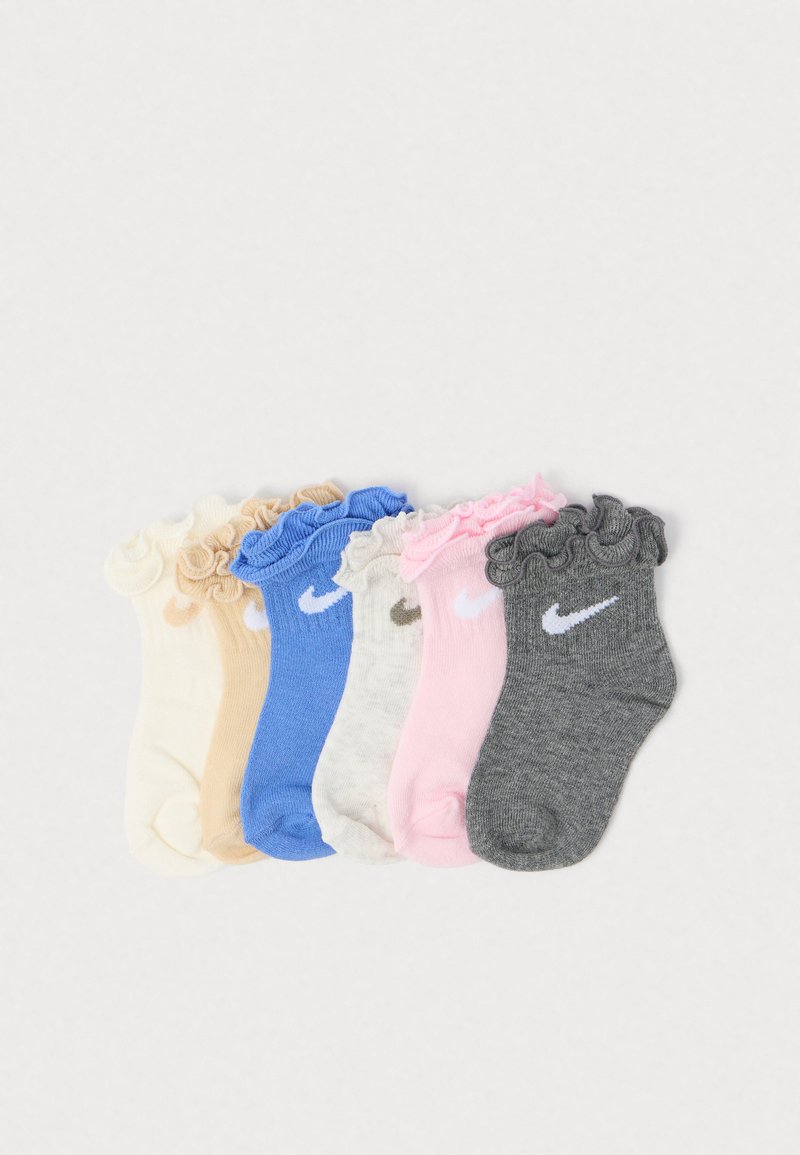 Kuusi paria sifonkisia Nike-sukkoja: kerma, beige, sininen, pilkullinen harmaa, vaaleanpunainen ja tumma harmaa, aseteltuna vierekkäin valkoista taustaa vasten.