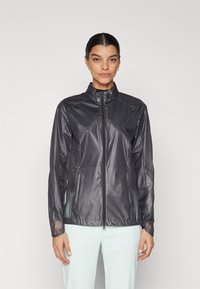 Svart, lätt vindjacka med hög krage, full dragkedja fram och långa ärmar. Har en slät, glänsande yta och minimal detaljering.