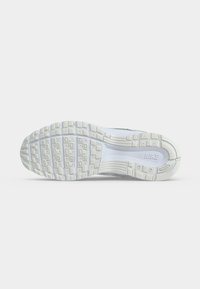 Λευκή σόλα παπουτσιού Nike με υφή στο πέλμα και το λογότυπο της Nike ορατό στο κέντρο σε απλό φωτεινό φόντο.