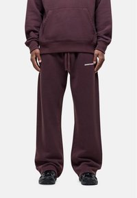 Bordeaux hoodie met kangoeroezak, gecombineerd met bijpassende ruime sweatpants met witte "GOODFORM" tekst, gedragen met zwarte sneakers.