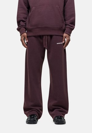 Burgunderfarbene Kapuzenjacke mit Kängurutasche, kombiniert mit passenden locker sitzenden Sweatpants, die weißen "GOODFORM"-Text tragen, und schwarzen Sneakers.