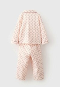 Pyjamakläder med långärmad topp och byxor i mjuk rosa tyg, prydda med ett upprepande blommönster och kontrasterande detaljer.