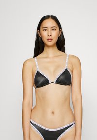 Svart sateng triangel-bh med tynne stropper og logo-printede detaljer. Matchende svart bikinitruse. Glatt tekstur, minimalistisk design.