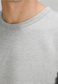 Graues Rundhals-T-Shirt aus einem weichen, strukturierten Stoff. Mit einem gerippten Halsausschnitt und einer lockeren Passform, versehen mit einem subtilen melierten Muster.