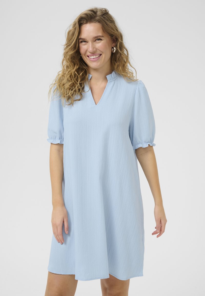 Rochie scurtă de culoare albastru deschis, cu mâneci scurte și un material texturat subtil, decolteu în V și mansete cu volane. Croi drept, fără modele.