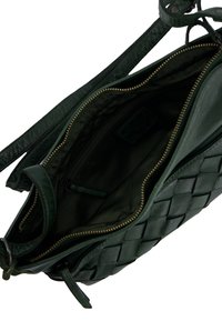 Green leather bag with woven exterior, a zipper closure, an inner zip pocket, and a smooth green fabric lining. Includes adjustable strap.