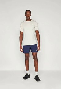 Hallist halli T-särk, tume sinised lühikesed püksid, mustad tennisetossud ja valged kõrged sokid. Lihtne disain, logo vasakul ülal. Mugav lõige, vabaaegne stiil.