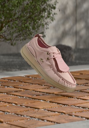 Scarpa in pelle rosa chiaro con punta arrotondata, dettaglio con lacci, etichetta rimovibile e suola in gomma color crema. Presenta cuciture lungo i bordi.