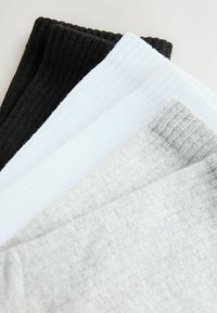 Dreiertset von Socken in Schwarz, Weiß und Hellgrau. Aus weichem, geripptem Stoff mit verschiedenen Farbtönen und ohne sichtbare Muster gefertigt.