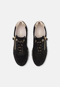 Černé semišové tenisky se zlatými detaily, s bočním zipem a černými tkaničkami, navržené s kulatou špičkou a s texturovanou podrážkou.