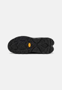 Suola di scarpe da trekking nere con un motivo di battistrada robusto per aderenza, bordi rinforzati e logo Vibram su una superficie in gomma testurizzata e resistente.