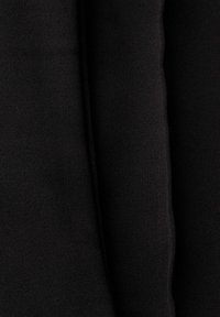 Gros plan sur un tissu noir en maille côtelée avec de doux plis montrant la texture et l'épaisseur.