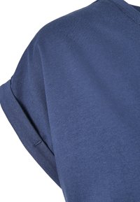 Close-up of a folded short sleeve on a blue cotton t-shirt with visible stitching and a smooth fabric texture.