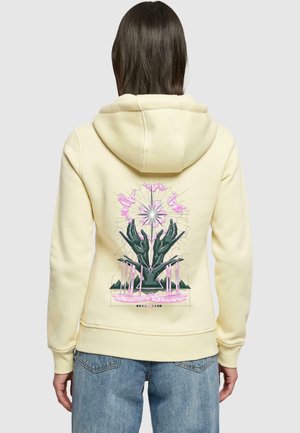 Gelbe Kapuzenjacke mit einem bunten Grafiken auf der Rückseite, die Hände und Blumen darstellt, mit einem lockeren Schnitt und strukturiertem Stoff.