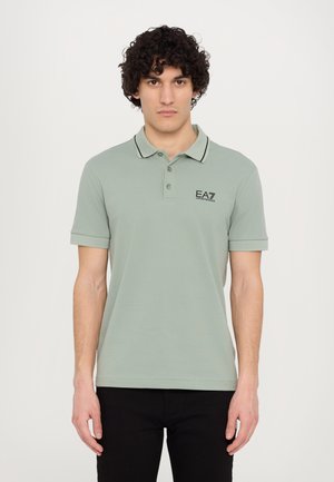 Light green polo shirt with a classic collar, black trim, and EA7 logo on the chest. Short sleeves and a fitted design.