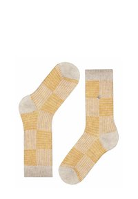 Karierte gelbe und cremfarbene Socken mit weicher Textur, die eine Mischung aus Strickmustern und einem kleinen dekorativen Knopfdetail auf einer Socke aufweisen.