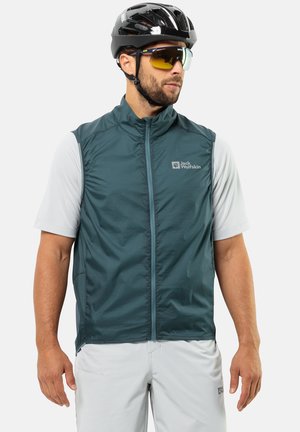 Green, sleeveless vest made of lightweight material with front zip and side pockets; worn over a light grey shirt. Ideal for cycling.