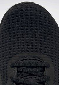 Černý svršek atletické obuvi s texturovaným síťovaným materiálem, plochými černými tkaničkami a zaoblenou špičkou. Žádné viditelné loga ani vzory.