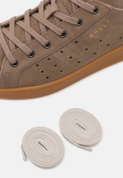 Brune ruskinds sneakers med rund tå, perforeret design for ventilation og flade beige snørebånd. Inkluderer to ekstra par snørebånd.