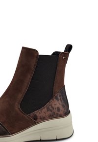 Braune Wildleder-Stiefelette mit schwarzen elastischen Seitenpaneelen und einem strukturierten, braunen Tierprint-Akzent. Mit einer gummierten Sohle und einem eleganten Design kombiniert.