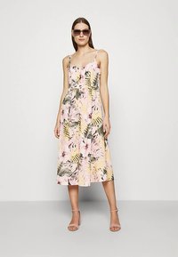 Florales Midikleid in Pastellrosa mit grünem und gelbem tropischem Blattmuster, mit dünnen Trägern, Knopfdetails und einem fließenden Schnitt.