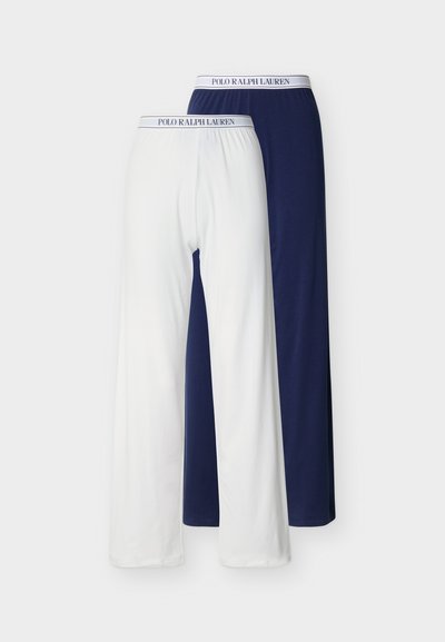 Δύο ζευγάρια παντελόνια lounge Polo Ralph Lauren σε λευκό και ναυτικό με ελαστικές ζώνες μέσης με λογότυπο, απλωμένα επίπεδα σε λευκό φόντο.