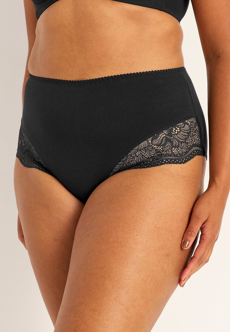 Svart höghöjd underkläder med spetspanel längs sidorna, slät textur och vågiga kanter.