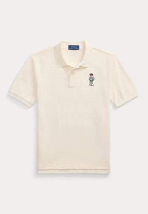 Camisa polo beige de algodón, con una tapeta de tres botones, mangas cortas y un logo de jugador de polo bordado en el lado izquierdo del pecho.