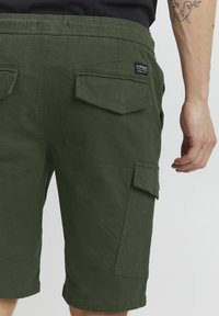 Olivgrüne Cargo-Shorts aus Baumwolle, mit zwei Gesäßtaschen, einer strukturierten Oberfläche und einem elastischen Bund mit Branding.