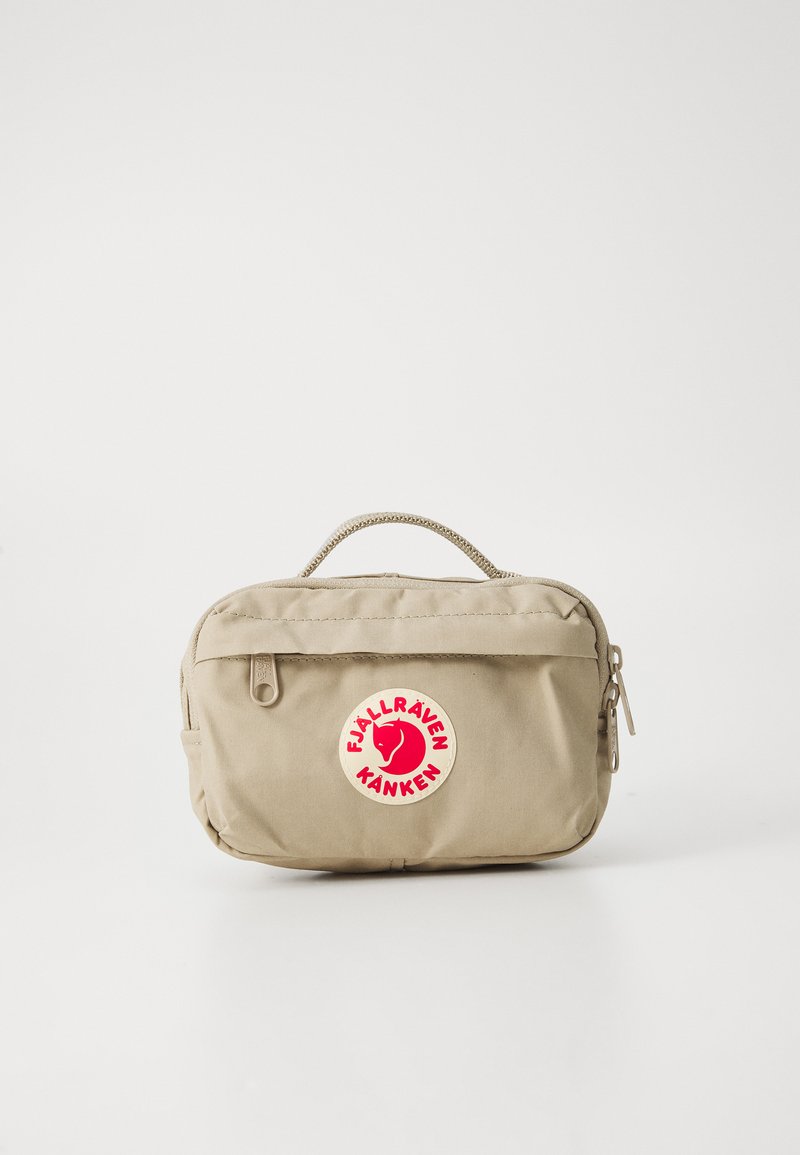 Pochette beige Fjällräven Kånken con tasca frontale con cerniera, manico in corda e patch con logo della volpe rossa su sfondo bianco.