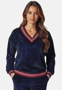 Pullover in velluto blu navy con scollo a V e colletto a righe rosse. Presenta maniche lunghe e una vita a coste con dettagli rosso e bianco.