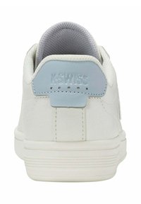 Baskets blanches avec une tige texturée, un empiècement au talon bleu clair portant un logo en relief, et une semelle en caoutchouc avec de légères rainures.