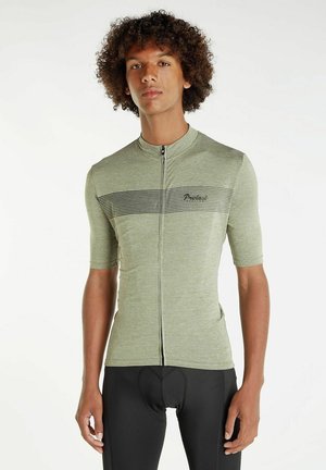 Maillot de cyclisme vert à manches courtes avec un motif texturé, fermeture éclair à l'avant et rayures noires horizontales. Associé à un short de cyclisme noir ajusté.
