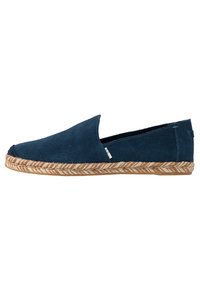 Zapato de ante azul marino sin cordones con una suela envuelta en yute, que presenta una textura suave y un sutil acento de logo blanco en el lateral.
